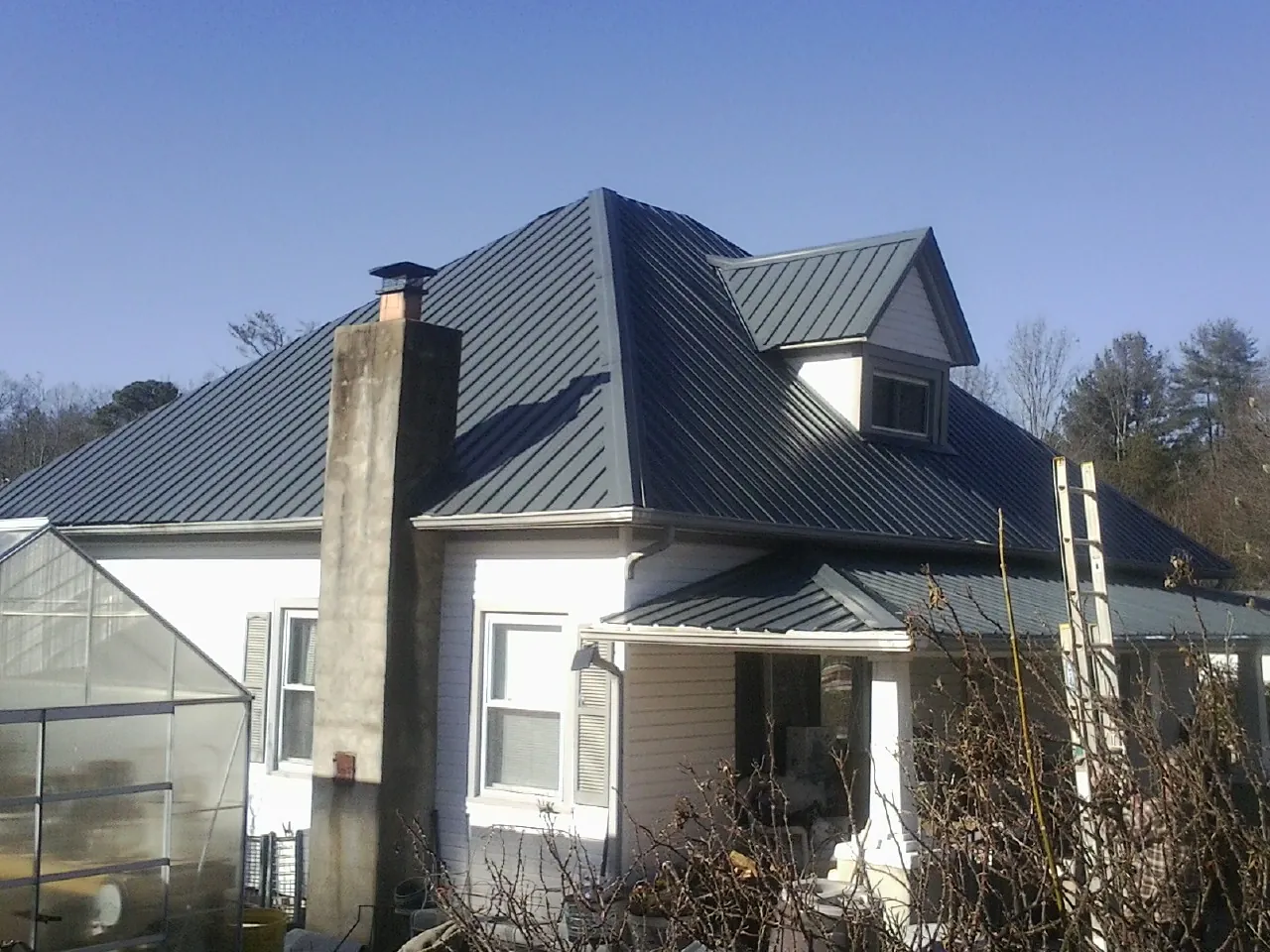 Dark blue standing seam metal roof on a white farmhouse with dormer — Slate & Tile Roof Repair by Roofing Brothers in Monteagle