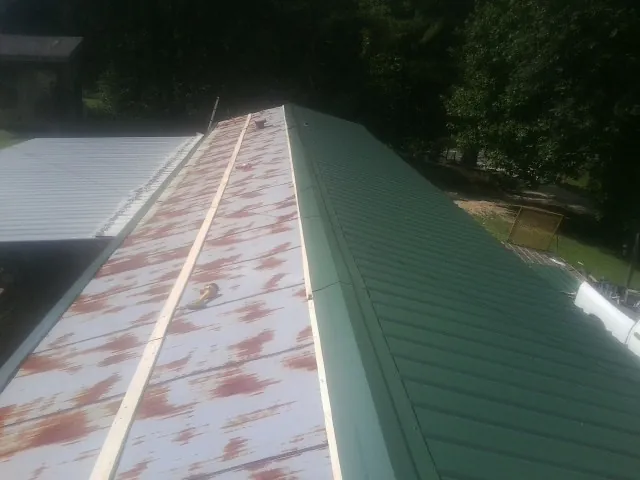 Old rusted panels beside newly installed green metal roofing — Wind Damage Roof Repair by Roofing Brothers in Monteagle