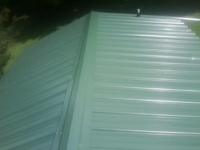New green metal panels meeting at the ridge of a roof — Flat Roof Repair work by our crew in Monteagle