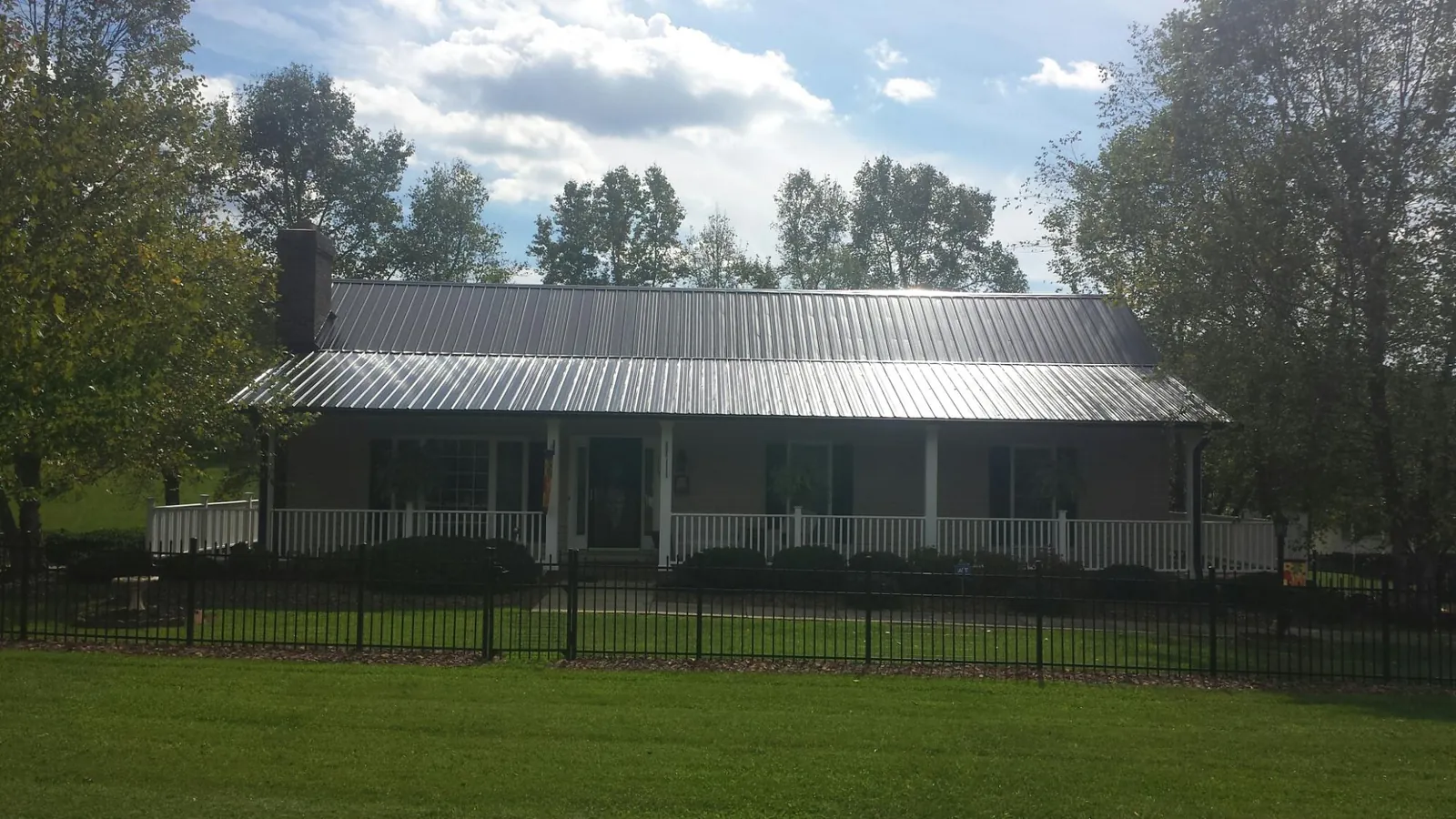 Gray metal roof on a brick ranch with a full width front porch — Gutter Guard Installation work by our crew in Monteagle