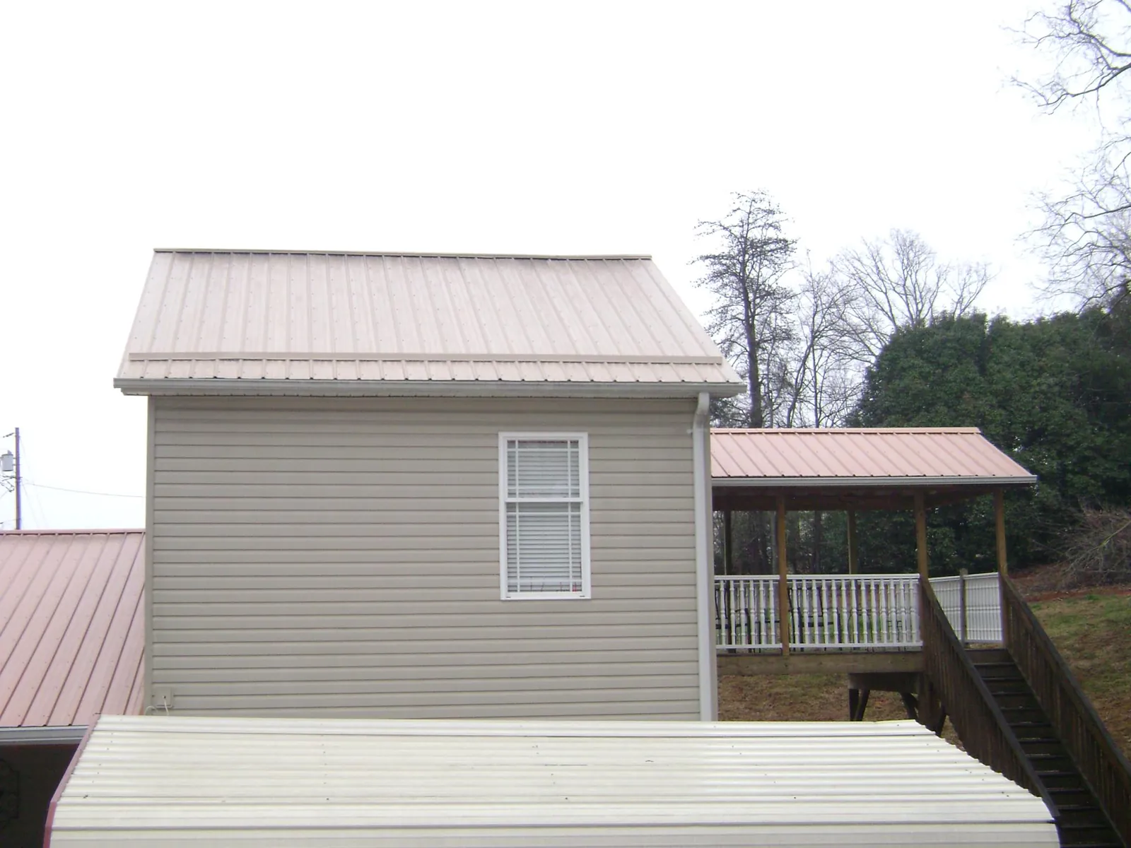 Tan metal roofs on a two story addition and attached porch, from a Roof Replacement job in Monteagle